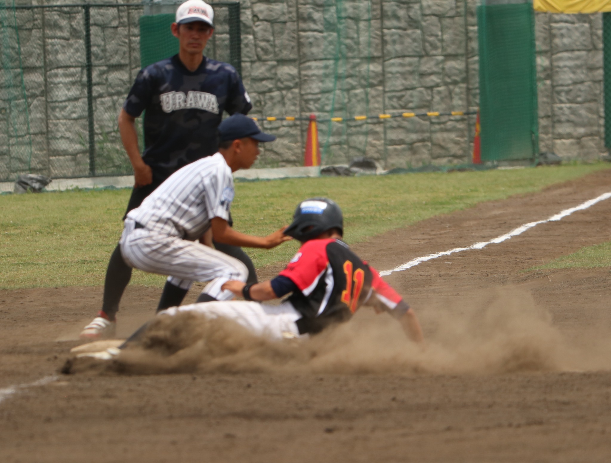 砂煙を上げてベースに滑り込む三鷹ボーイズの選手